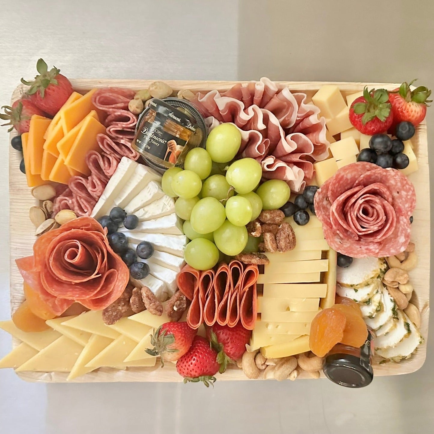 A charcuterie board featuring an assortment of cheeses, meats, fruits, and nuts, arranged elegantly on a platter.