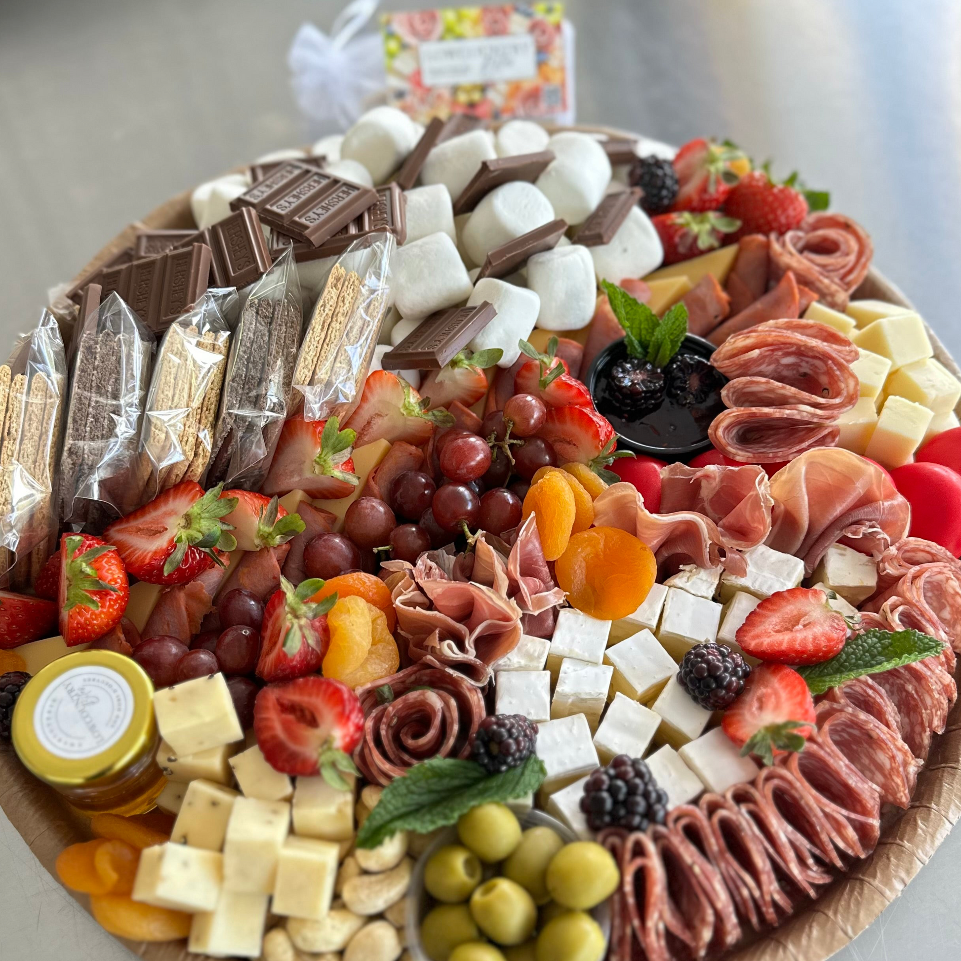 Assorted charcuterie board with meats, cheeses, fruits, and pastries on a wooden board.