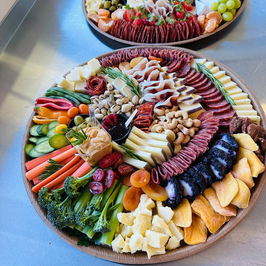 Platter of assorted meats, cheeses, vegetables, and fruits on a board.