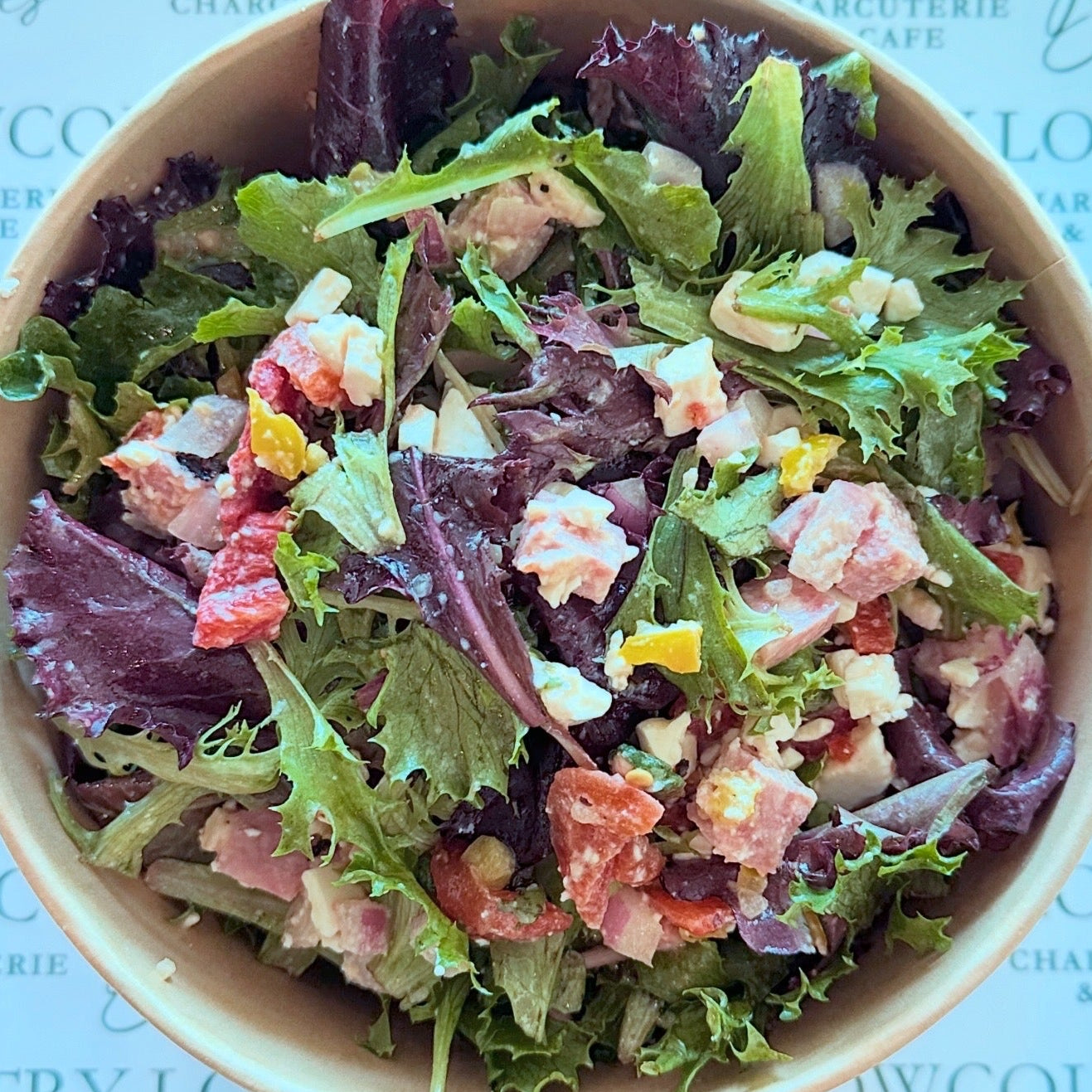 Bowl of salad with visible ingredients on a branded background